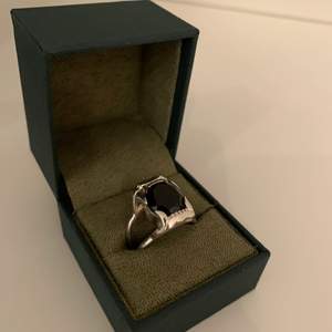 Populär ring i silver med svart sten från Maria Nilsdotter. Modellen heter jaw stone ring. Den är i väldigt gott skick samt nypolerad i butiken. Kvitto finns. Medföljer även original förpackning, box och påse. Nypris ca 5000
