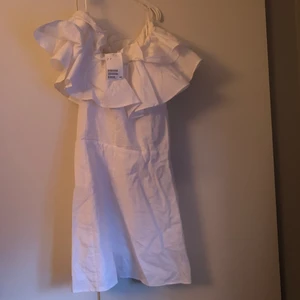 Vit klänning - Helt ny klänning från hm med lapparna kvar, jätte fin passform med oneshoulder och volanger❤️ kan mötas på lidingö annars blir det post som köparen står för OBS! Litet hål vid dragkedjan lätt att sy ihop💓