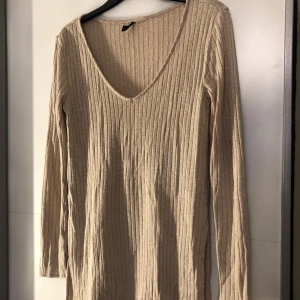 Beige tröja med slits - En v-ringad tröja med slits som är ribbad, i beige färg. Köpt från H&M. Storlek S. Välanvänd dock som ny.