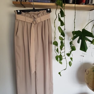 Beigea byxor  - Sköna, stretchiga o midjan, skärp medföljer, dock lite trasigt så därför satt ihop med en säkerhetshål! Lätt att fixa om man vill! Lappen där storleken står på är också lite trasigt, men inte byxorna i sig🌸🌸