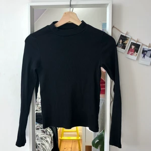 Långärmad svart ribbad halvpolo - Långärmad svart ribbad halvpolo från Monki, använd men i bra skick. Perfekta basplagget!