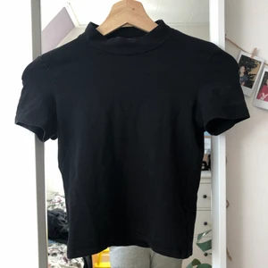 Kortärmad svart halvpolo - Kortärmad svart halvpolo från Monki, använd men i bra skick. Stretchig så passar även större storlekar. Har lossnat en tråd på ena ärmen men inget man tänker på alls. Perfekt basplagg!