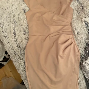 Klänning från NELLY - En fin och enkel klänning i beige/nude från NLY som är V-ringad. Använd 2-3 gånger. Storlek XS. Fler bilder kan skickas vid intresse