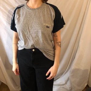 Champion T-shirt - En champion t shirt i grått med blåa armar och vita ränder. Frakt tillkommer på 50 kr. 