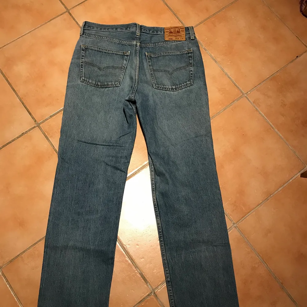 Ljusblåa American Classic jeans i väldigt gott skick. Det enda irriterande med byxorna är att det inte finns dragkejda eller knappar att stänga med (förutom den längst upp). Man stänger byxorna med carboardband. W36 L34. Finns att hämta i Rågsved.. Jeans & Byxor.