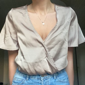 V-ringad body - Jättefin body i satinliknande material från NAKD. Aldrig använd.