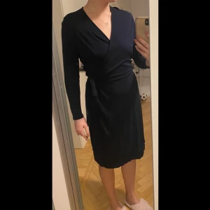 Filippa K omlottklänning storlek M-XL - Jättefin mörkblå klänning från Filippa K, endast använd en gång på ett dop så den är i nyskick. Passar från en större M till en XL då den är strechig men tyvärr för stor för mig nu. Fler bilder kan skickas om så önskas!🌟 Skickar endast spårbart eller kan mötas upp!