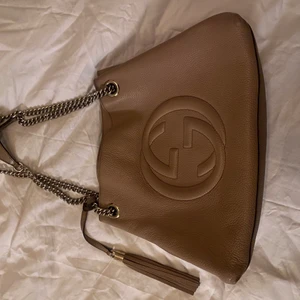 GUCCI SOHO CHAIN LETHER SHOULDERBAG - Gucci väska med verifierat serienummer! Den är i väldigt fint skick och passar i princip till allting. Väskan är i beiget länder, har guldkedjor samt en väldigt fin läder tofs! Mer bilder samt info kan skickas :). Nypris 19 000