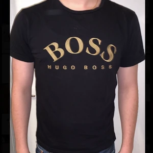 Hugo Boss T-shirt - Hugo Boss T-shirt storlek S för men. Svart med guld text, enkel och riktigt fin tröja! Tröjan är givetvis äkta, hör av dig om du vill se fler bilder! (Inga skador på tröjan precis som ny!)