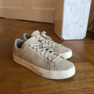 Adidas begie sneakers strl 39 1/3 - I princip oanvända sneakers från adidas. Dom märken som finns har tillkommit genom att stå i hallen och på vinden, men går antagligen att tvätta bort.