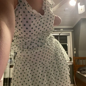 Volang klänning - En fin volangklänning som är vit med mintgröna prickar på. Sitter som ett smäck och har en dragkedja från svanken till ryggen. Justerbara axelband och gör att den därför passar XS-M. Vet ej märket men köpte den till min skolavslutning men hade den på distans så har aldrig användt den. Nypris 400kr men säljer för 275kr❤️ kunden står för frakten😊