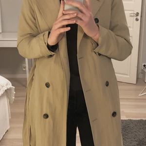 Beige kappa från Kappahl  - Snygg kappa från Kappahl. Köpte den för några år sedan men den är fortfarande i bra skick. Den är mörkbeige och har ett skärp till, som går att ta bort om man vill🥰 Köparen står för frakten! 