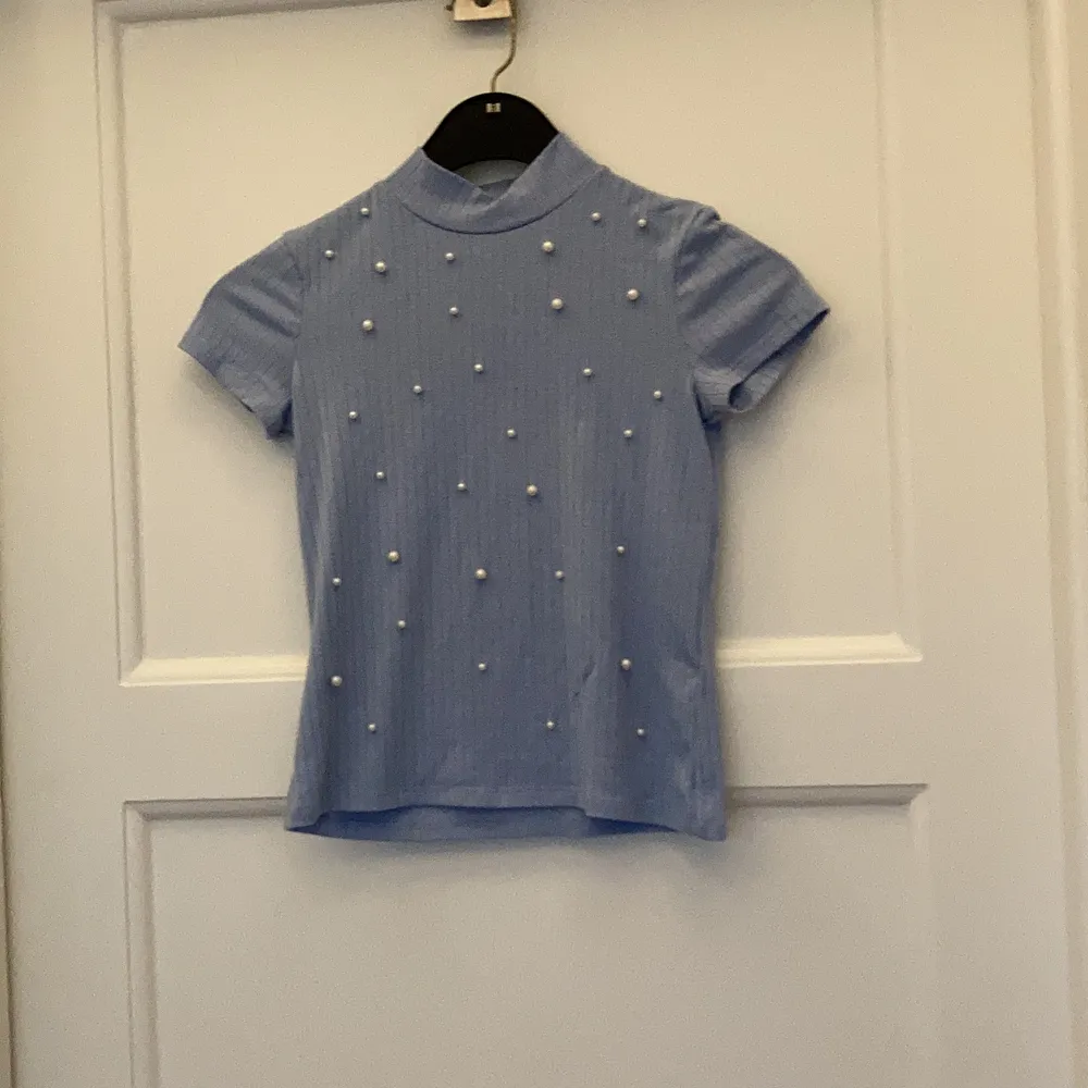 Jag säljer en blå tröja med pärlor och krage. Den är jättefin till vår eller sommar och har ett ribbat material. Jag kan mötas upp i Täby/Danderyd annars tillkommer frakt.. T-shirts.