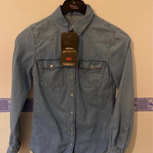 Helt ny Levis jeansskjorta! - Helt ny märkes- jeansskjorta från Levi’s. Har bara hängt i garderoben och inte kommit till användning, lapparna sitter till och med kvar! Så den är ny!  Storlek xxs men passar som xs/s också!  Inköpt för 769kr på rea! Säljer såklart lite billigare då jag inte kan lämna tillbaka den, men ett riktigt fynd för dig som vill ha nytt till begagnat pris!#levis #levisoriginal