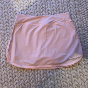 Nike tenniskjol - Tenniskjol från Nike i storlek XS. Säljes då jag har lite för många tenniskjolar. Går sjävklart också att använda som vanlig kjol. Har dessvärre en liten fläck på högersidan precis vid kanten mot midjebandet (se bild), därav billigt pris. Syns knappt när man har en tröja till. Annars i väldigt fint skick, använd fåtal gånger. Nypris är ca 500kr. Spårbar frakt tillkommer på 51kr