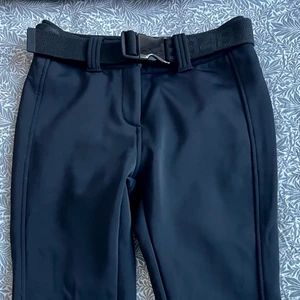 Svart tight Skidbyxa dam Altitude 8848  - Superstretch softshell, tight passform. Vind- och vattenavvisande finish. Mjuk fleece på insidan. Snölås nedtill och dragkedjor på baksidan. Bälte medföljer. Jättefint skick! Nypris 1800kr.