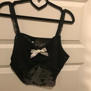 Svart nätt topp - Svart nätt topp från shein curve. Med döskallar och en vit rosett storlek 0LX