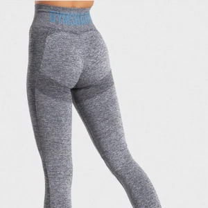 Gråa Gymshark träningsbyxor - Gråa högmidjade träningsbyxor med blå text i svanken💕 Dem är slutsålda på gymshark hemsida (där bilderna kommer ifrån)!                                Otroligt fin passform och formar midjan väldigt mycket! 