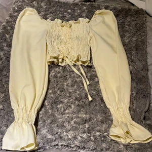 Smockad croppad tröja - Smockad croppad långärmad tröja med justerbar drag fram. Kan både användas som off shoulder. I strl Xs-S och nyskick. Har även resårband för att inte tröjan ska åka ner. 