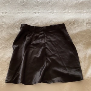 Kort Satinkjol - En kort svart satinkjol, väldigt fin och bra kvalite då den knappt är använd alls Max 1 gång. Köptes i somras och säljs pga att den är för stor för mig.