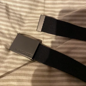 Svart skärp - Svart brett skärp från Urban Classics med metallspänne, använt ett fåtal gånger. Köparen står för frakt (ca 24 kr icke-spårbart, 49 spårbart)