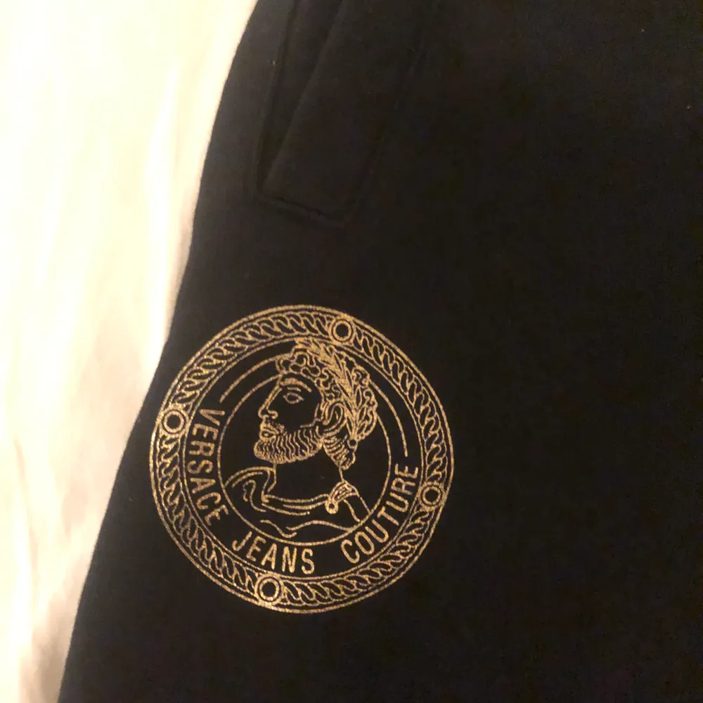 Versace mjukisbyxor, svarta med guld symbol. Skick 8-9/10 Storlek S/M. Jeans & Byxor.