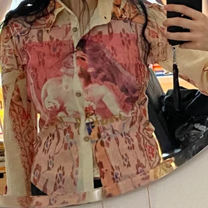 Fin skjorta - Superfin skjorta med tjej på framsidan. Röda rosetter på armarna och röd blomspets därbakom. Står storlek M men mer S/M.