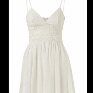 Vila,vit kort klänning - Klänningen är från vila. Den är kort perfekt för studenten/sommaren.överdelen har textur på sig i form av ett mönster som liknar spets. ”Kjolen” är fluffig och har klänningen har en under kjol vilken gör att den inte är genomskinlig. Axelbanden är justerbara. Klänningen har en dragkedja på ryggen.