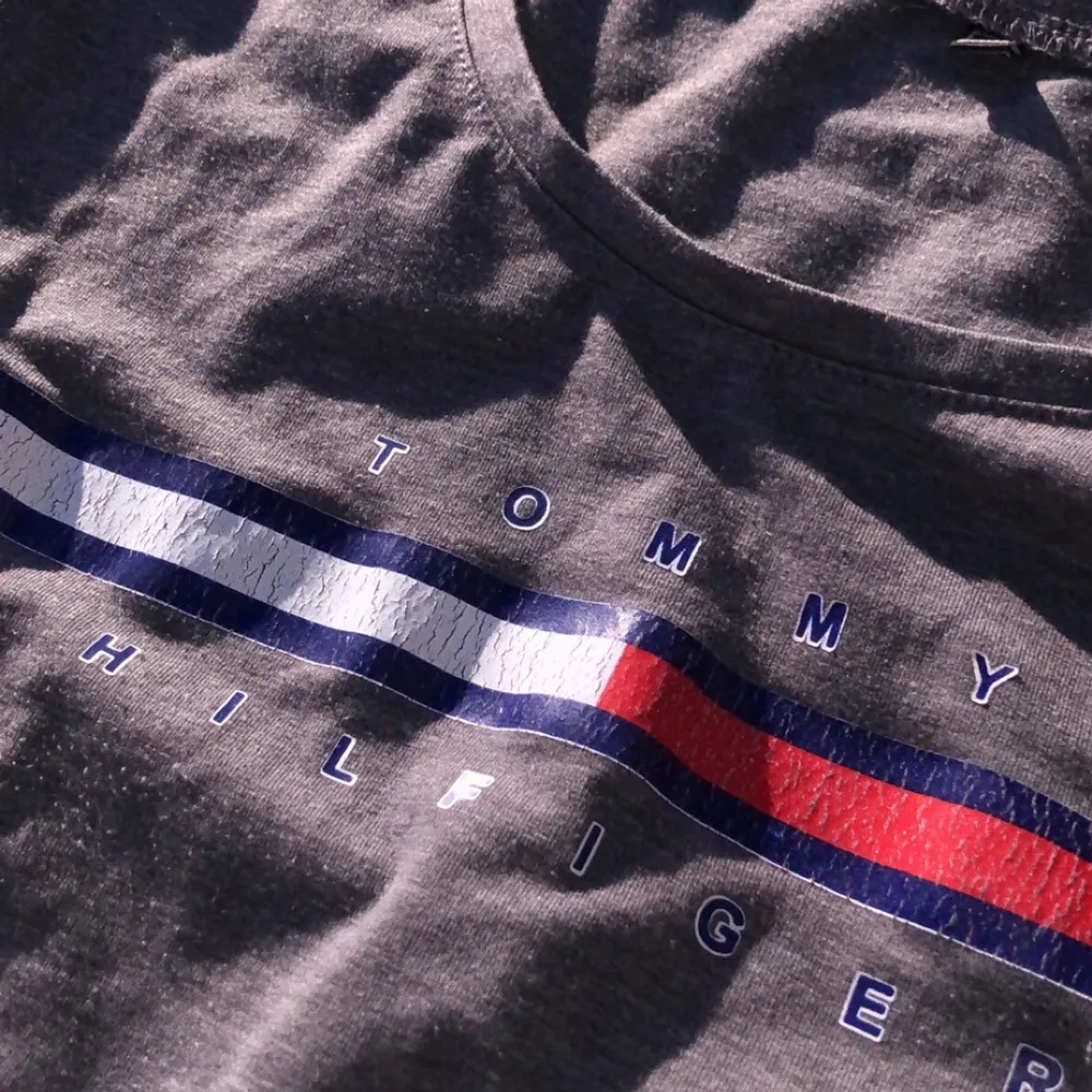 En grå, hyfsat tajt t-shirt från Tommy Hilfiger. Märket är rätt slitet då den är använd ett par år. . T-shirts.