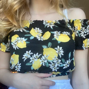 Gul topp - Väldigt fin croppad top med citroner på! Sitter väldigt fint över axlarna och har en resår under bysten. Köpt från Gina för några år sedan och säljs därför inte längre. Väldigt tunt tyg men inget som är genomskinligt, väldigt bra till sommaren!