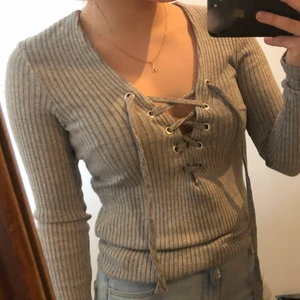 En ribbad långärmad  - Det är en ribbad grå långärmad med snörning i v-ringningen, aldrig använd 