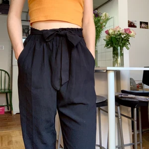 Svarta byxor med snörning i midjan - Snygga och sköna svarta byxor i skönt tyg. Byxorna är i storlek S men passar även XS då midjan kan dras åt och knytas med ett band. Jag är 170 cm. Byxorna är också snygga uppvikta. De är i gott skick.