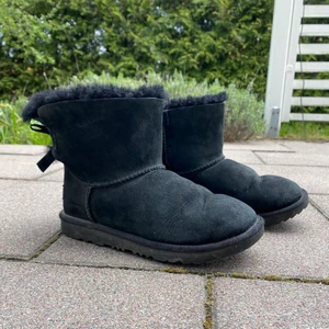 Svarta Uggs med rosett i stl. 33 (stor i storleken) - Ett par svart uggs med rosetter i bra skick. Behandlade med impregneringsmedel. De är i storlek 33 men är stor i storleken. Kartongen finns kvar och skickas med.         Frakt ingår inte