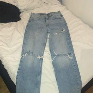 Ett par blåa högmidjade jeans med hål ifrån Gina tricot. Str 36. Köparen står för frakt 