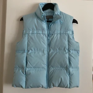 Babyblå dunväst äkta dun - Superhärlig och varm äkta dunväst i världens finaste baby blå!💘fint skick, en liten missfärgning vid dragkedjan (se bild 3) som knappt syns!Skickas spårbart för 66kr🦋  många intresserade så vi kör budgivning! Börjar på 200kr+frakt och höjs med 10kr per bud. Högst bud: 320kr+frakt