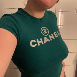 Asclean vintage baby tee (fejk Chanel)  - Grön t-shit med en silver text och ett silvrigt chanelmärke( fejk). Snygg med både högmidjade och lågmidjade jeans!!! Den är uppskattningsvis en small men jag är vanligtvis en medium large och kan fortfarande ha den. Lite liten för mig i min smak dock, därav säljer jag den.