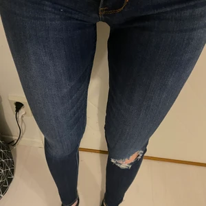 Blåa jeans - Blåa jeans med slitning på vänstra knät. Från hollister i storlek w25, passar xs.