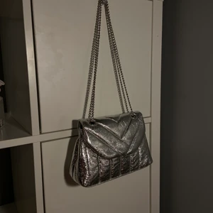 Silvrig väska  - En skit cool silvrig väska från pull & bear! Kan ha ett långt band men också göra det kortare som på bilden. 