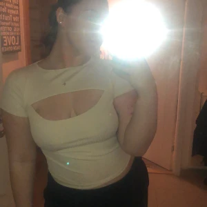 Detaljerad t-shirt  - En fin beige/benvit t-shirt med tippat mönster, öppning vid brösten