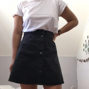  - Svart, Highwaist,  jeanskjol  med knappar från Monki som är köpt här på Plick. Den har inte kommit till användning så jag säljer den vidare. 