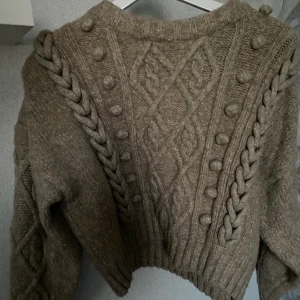 H&M stickad tröja - Stickad tröja men fina detaljer på, storlek M. Den är croppad så den sitter precis under navlen på mig, 167cm. Köpte i vintras och använt 2 gånger. Som ny!
