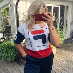 FILA T-shirt  - Säljer en FILA T-shirt som är köpt på Madlady. Tryck på bröstet + båda armarna. Väldigt snygg med kommer tyvärr aldrig till användning. Är i fint skick (dock en liten vit ”fläck” på trycket från ett strykjärn) Storlek M! 50kr + frakt! 🥰