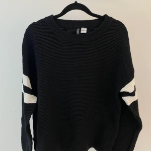 Ribbstickad tröja från H&M - Svart ribbstickad tröja från H&M med vita detaljer på ärmarna. Storlek S och har oversize fit. I nyskick.