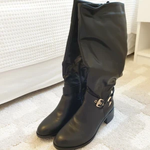 Svarta OANVÄNDA stövlar!   - Helt oanvända svarta stövlar med lite fodring inuti. De har en gulddetalj (guldskärp) och dragkedja. Önskar du fler bilder kan jag bistå med det. 