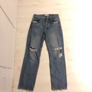Raka Zara jeans - Snygga raka Zara jeans med slitningar i storlek 34.  