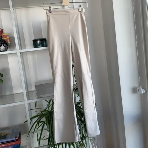 Beiga byxor i läderimitation  - Ett par byxor från Gina tricot i läderimitation.   Byxorna har inga fickor och en dragkedja på sidan. I storlek xs men passar mig som normalt sett brukar ha s/m i byxor. Bootcut modell. Använda 2 gånger. Frakt ingår 📦 