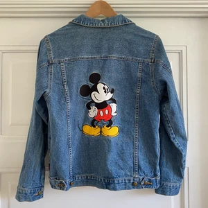 Jeansjacka Disney  - Jeansjacka köpt second hand med Musse pigg broderad på ryggen. Fickor i sidan och mindre brodyr fram. Står på lappen att den är från Disneyland i Paris. Barnstorlek men skulle säga typ strl S-M. Hämtas i Malmö eller skickas, då tillkommer frakt
