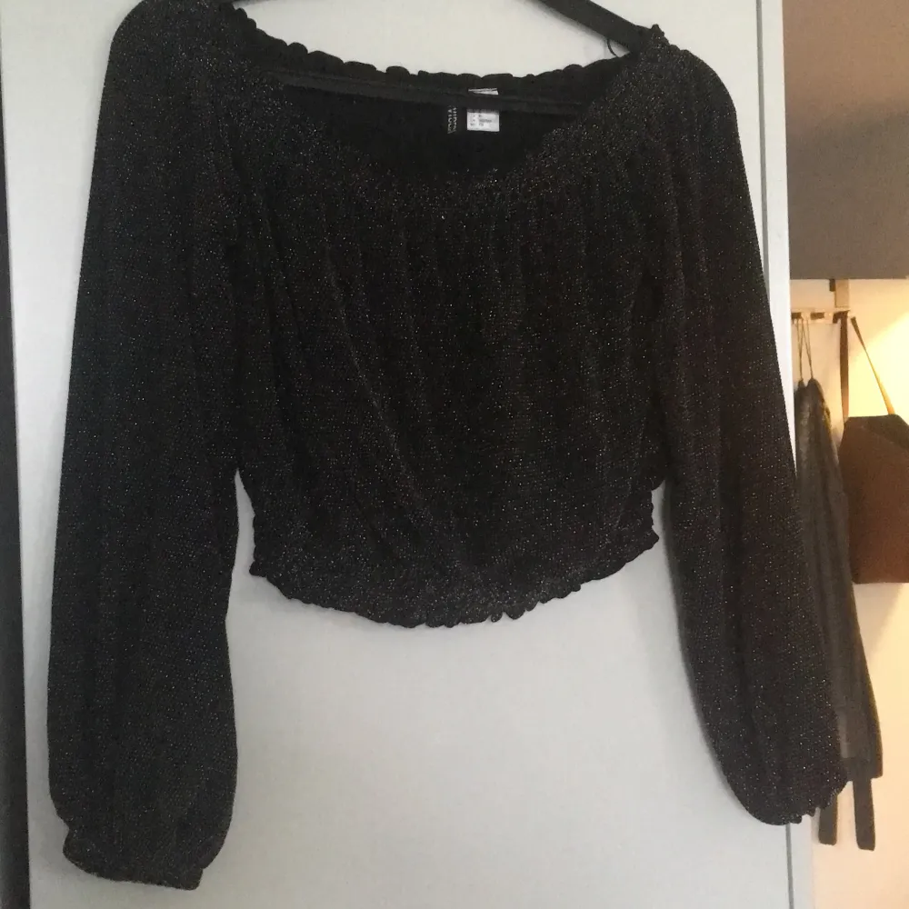 Svart crop top med glittertråd i. Offshoulder om man vill annars funkar även på axlarna. . Toppar.