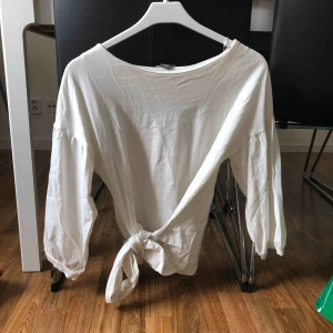  - Vit tröja med knytning i midjan och ballongärmar, i fint skick! Frakt tillkommer