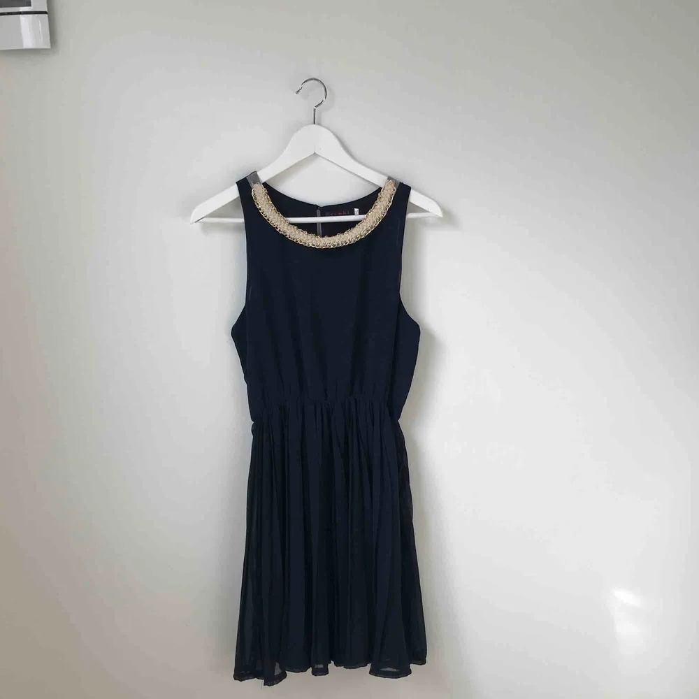 Marinblå klänning med gulddetaljer. Nypris 499kr. Använd ca 3 gånger, ser ut som ny. Köparen står för fraktkostnad enligt postens portotabell. . Klänningar.